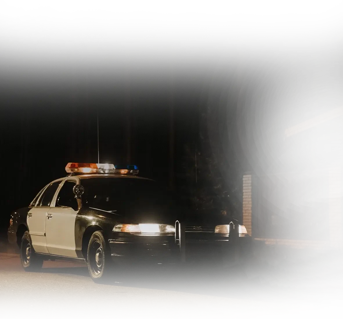 Police patrol car parked on a dark road at night with emergency lights illuminated